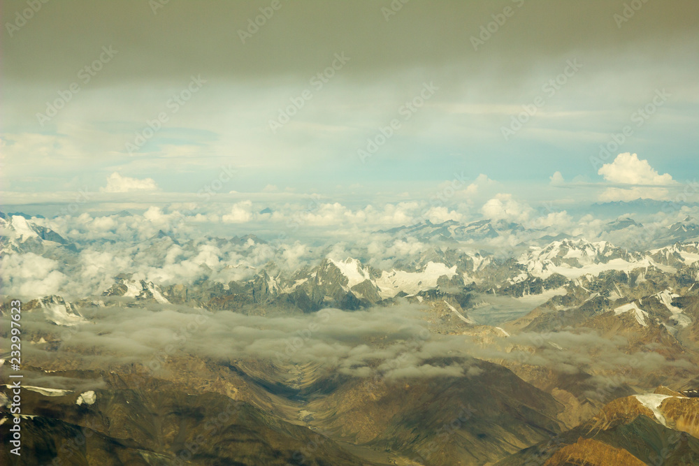view of the mountain desert valley with snowy peaks and clouds from a height