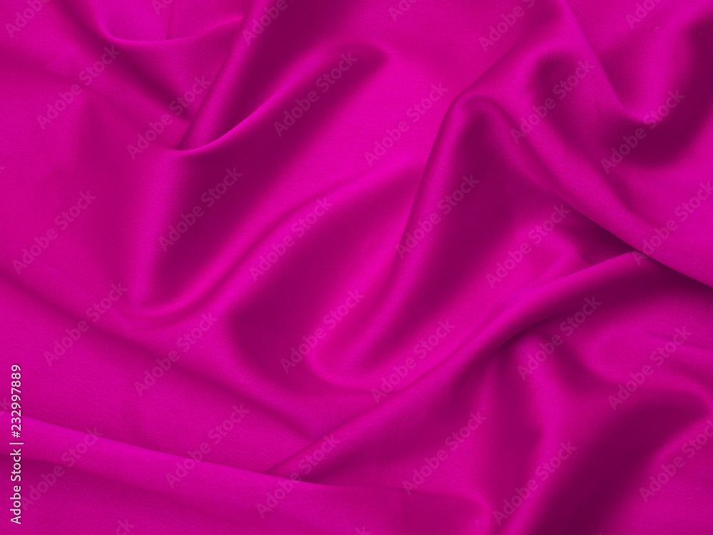 Fototapeta premium Pink fabric is laid out waves. Pink silk fabric for background or texture.