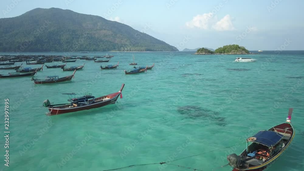 Top of traditional Thai boats, white sand beach, beautiful clear emerald sea, aerial drone view on tropical island, Ko Lipe, Thailand. Top of traditional Thai boats, white sand beach, beautiful clear emerald sea, aerial drone view on tropical island, Ko Lipe, Thailand.