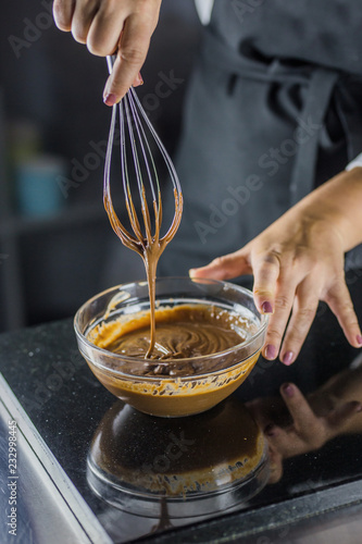 Chef is hindering chocolate with a whisk raising a whisk, photo on black background close up photo