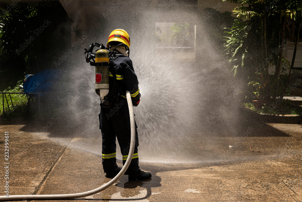 Naklejka premium Firefighters with extinguisher spraying high pressure water to fighting the fire flame in an emergency situation.