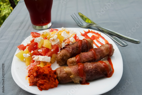 Chevapchichi. Meat sausages with vegetable salad, ketchup and adjika on white plate. Dish of Balkan cuisine. photo