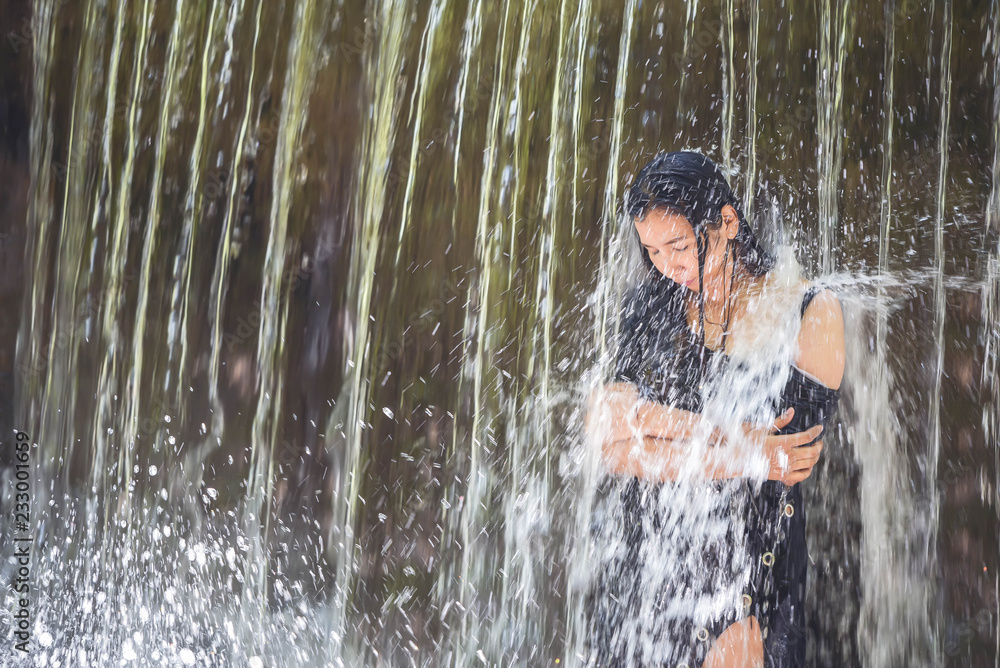 Women peace and playful bathing under waterfall. Beautiful Asian women