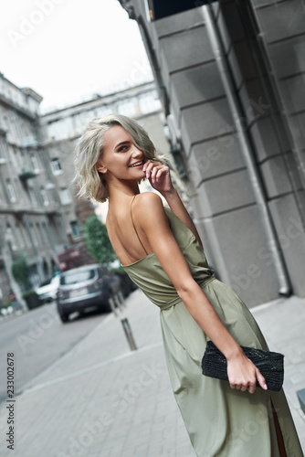 Fashion. Young stylish woman walking on the city street looking back smiling playful close-up