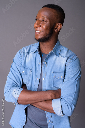 Young handsome African man with short hair against gray backgrou