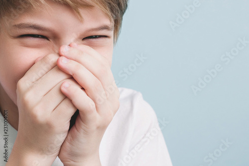 Laughing boy covers his mouth with his hands