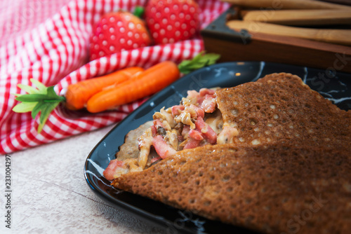 Black wheat and wheat galette topped with cooked ham and emmental cheese