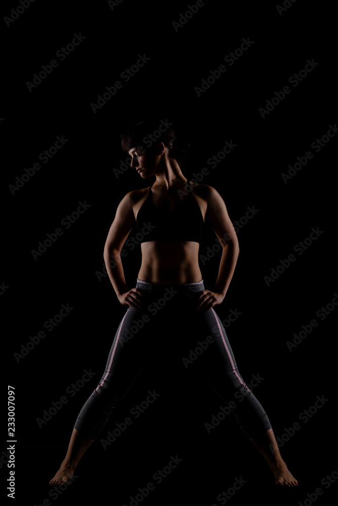 fitness girl posing against black background