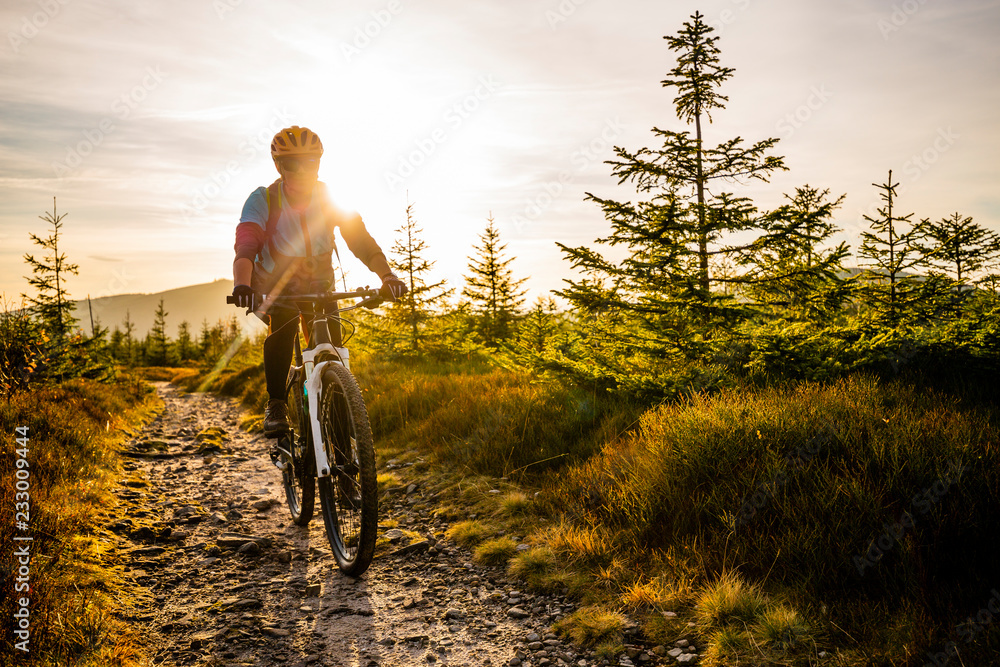 Cycling woman riding on bike in autumn mountains forest landscape. Woman cycling MTB flow trail track. Outdoor sport activity.
