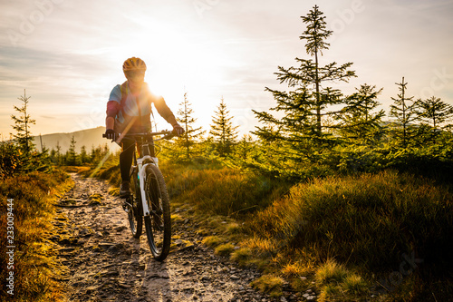 Cycling woman riding on bike in autumn mountains forest landscape. Woman cycling MTB flow trail track. Outdoor sport activity. photo