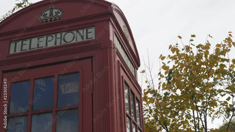 A red telephone booth and yellow tree branches. A red telephone booth and yellow tree branches.