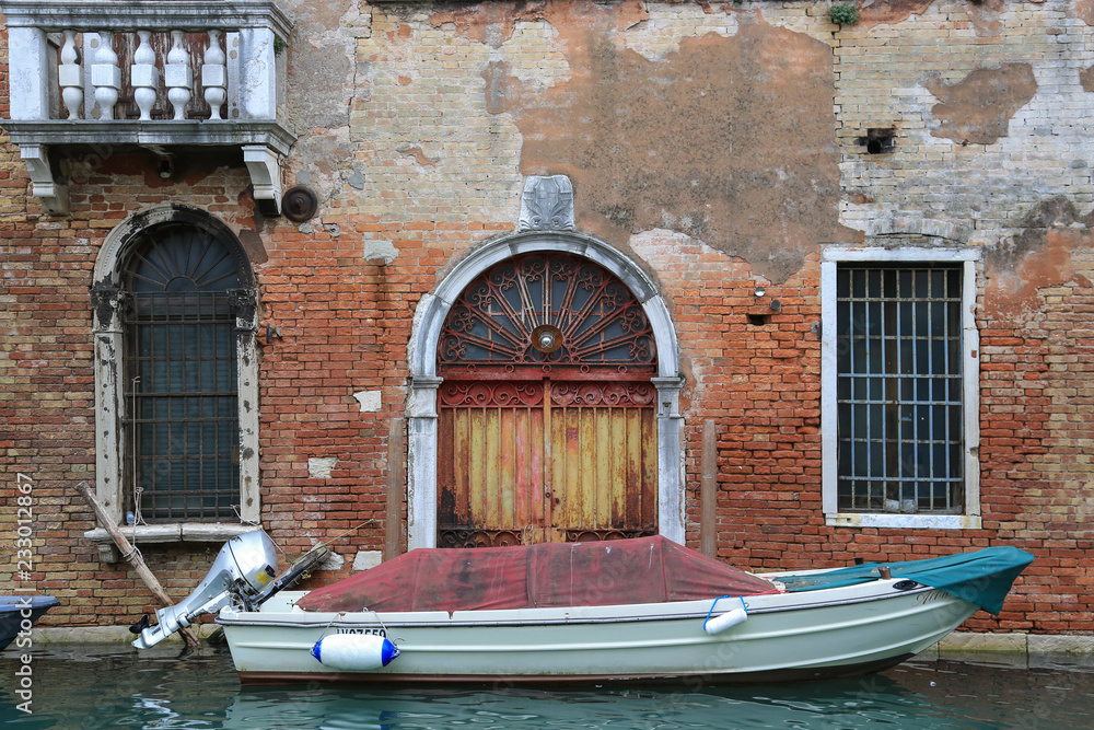 Obraz premium Venedig bei Hochwasser: Alte verwitterte Fassade und Tor mit Boot an einem Kanal im Stadtteil Cannaregio