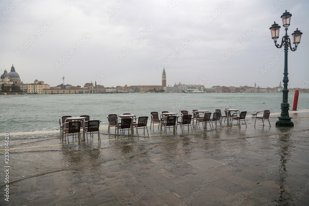 Venedig bei Hochwasser: Tische und Stühle eines leeren Restaurants Cafés im Wasser an der Fondamenta delle Zitelle (Giudecca) mit Blick auf die Stadtteile San Marco und Dorsoduro