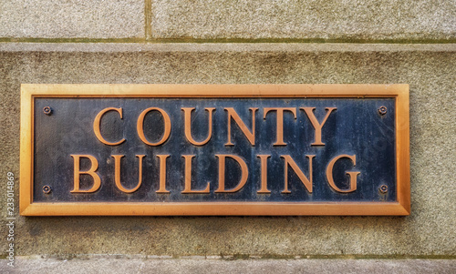 Exterior sign that reads "County Building" in brass letters. Close up. Graphic resource.