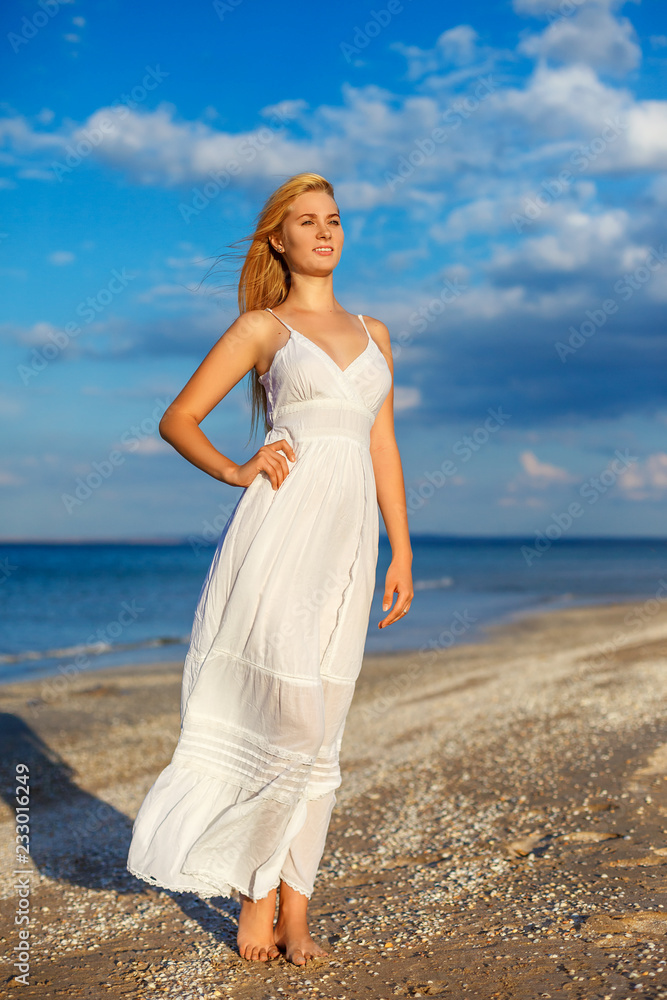 beautiful young woman in white dress by the sea in the sun