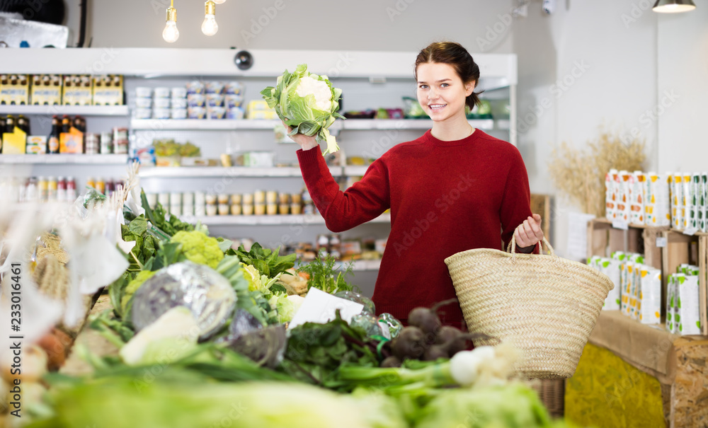Fototapeta premium cheerful young girl buying cauliflower at market