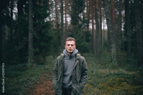  Caucasian young man in a forest in a green jacket. © velimir