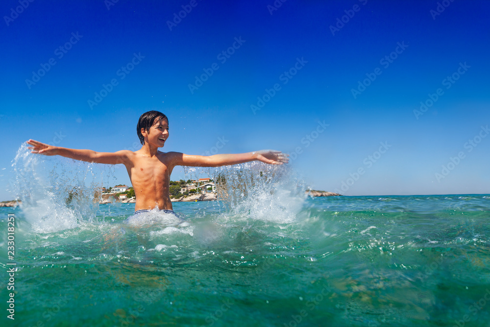 Happy teenage boy playing in water at the seaside