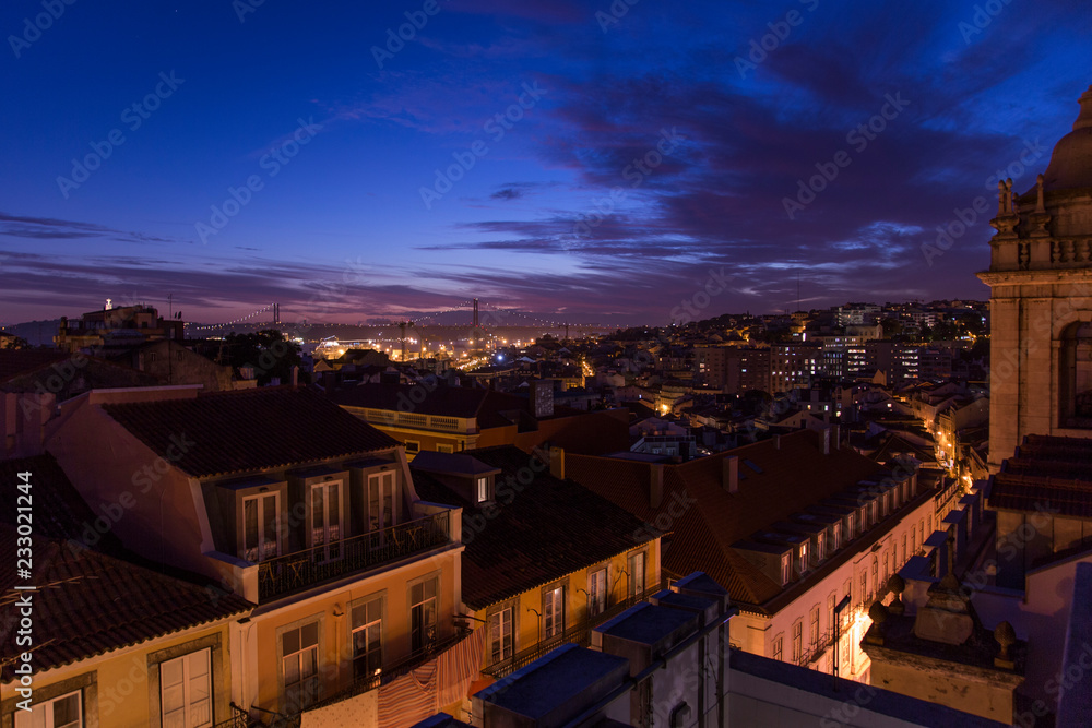 Beautiful sunset night view on bridge and house roofs at rooftop bar in city Lisbon, Portugal, Europe