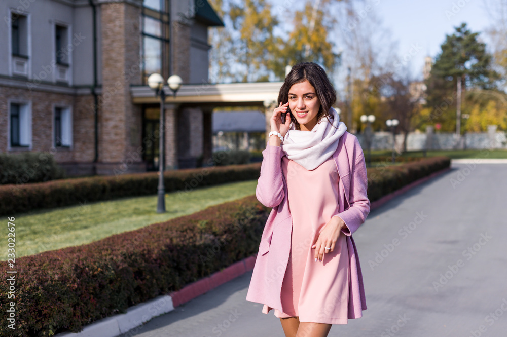 portrait of a young beautiful brunette woman on the street, autumn afternoon in warm seasonal clothes, women's urban street fashion, warm colors