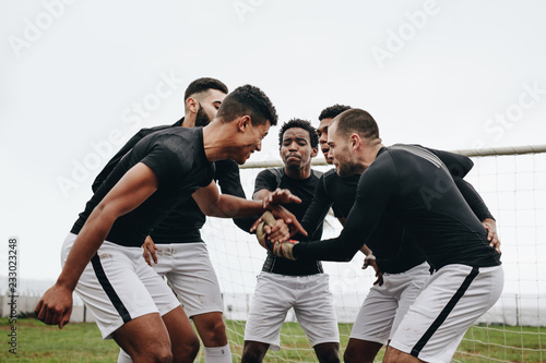 Fototapeta Naklejka Na Ścianę i Meble -  Soccer players joining hands standing in a huddle