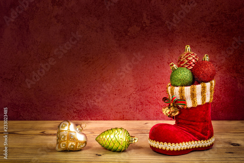 Ein Nikolaus Stiefel mit Christbaumkugeln vor einer roten Wand photo