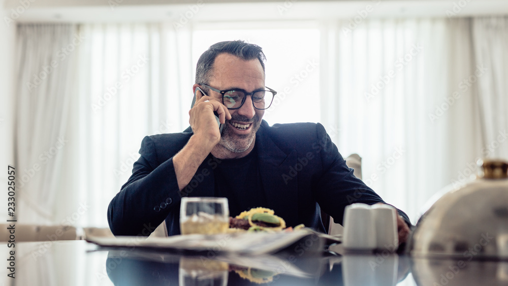 Businessman having lunch and talking on phone in hotel room Businessman having lunch and talking on phone in hotel room