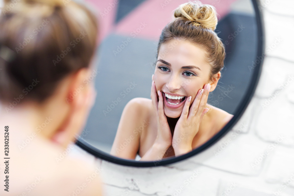 Young woman cleaning face in bathroom mirror - obrazy, fototapety, plakaty 