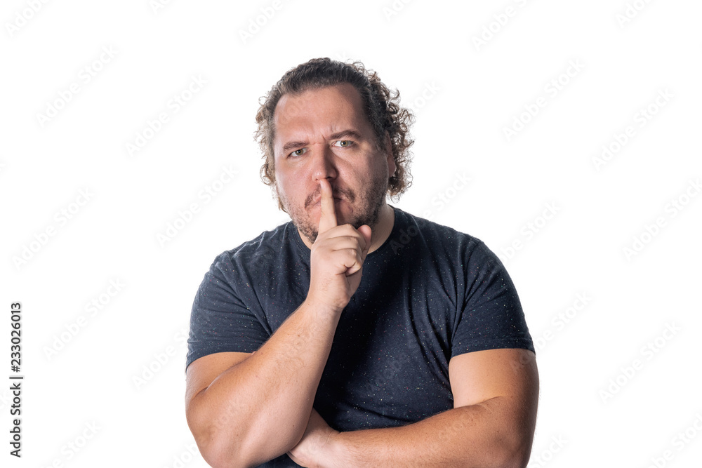 Portrait of handsome man cowering his mouth with his finger and looking at camera while standing against white background Portrait of handsome man cowering his mouth with his finger and looking at camera while standing against white background