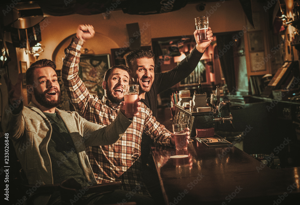 Fototapeta Old friends having fun and drinking draft beer at bar counter in pub