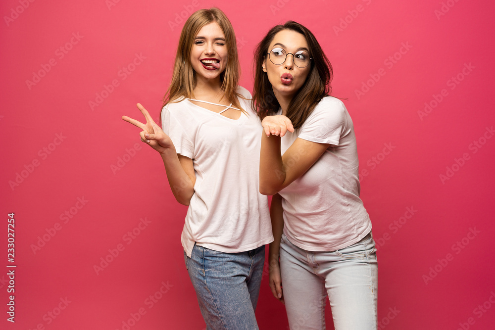 Two exited woman having fun and raising hands up. Standing on pink background. Lucky mood. Two exited woman having fun and raising hands up. Standing on pink background. Lucky mood.
