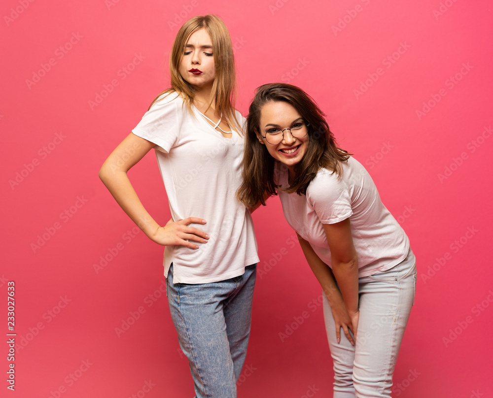 Two exited woman having fun and raising hands up. Standing on pink background. Lucky mood. Two exited woman having fun and raising hands up. Standing on pink background. Lucky mood.