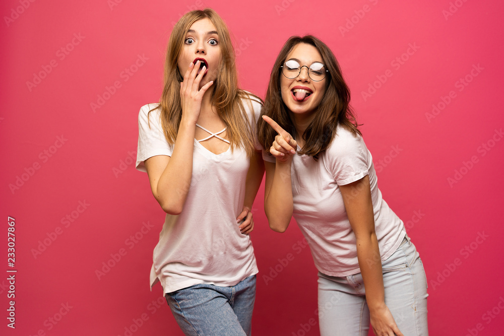 Two exited woman having fun and raising hands up. Standing on pink background. Lucky mood. Two exited woman having fun and raising hands up. Standing on pink background. Lucky mood.