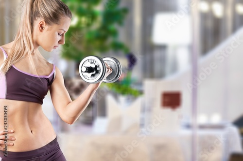 Close-up attractive young woman holding dumbbell on blurred