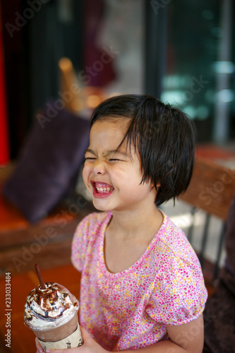 Portriat Asian little girl drinking blended ice chocolate with funny face