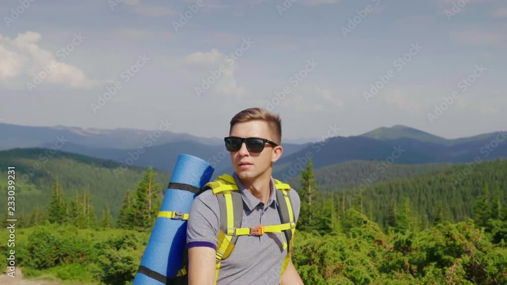 Forward to conquer the summit. A young, purposeful man with a backpack rises uphill Forward to conquer the summit. A young, purposeful man with a backpack rises uphill