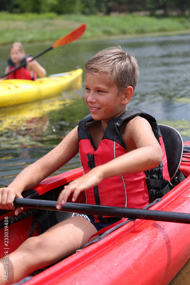 Obraz premium background. handsome guy sits in a kayak in a red life jacket and holds a paddle