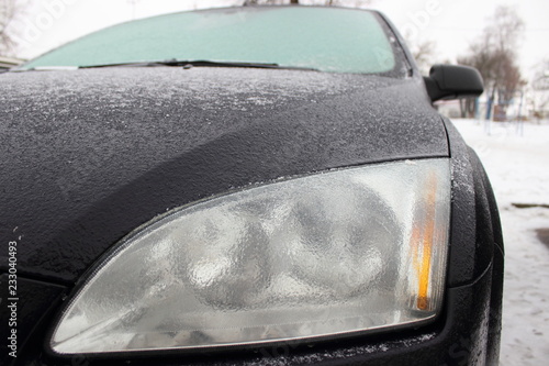 Car with frosted frost-covered body in winter - driving safety, heating, preparation for the trip, front view to headlight lamp photo