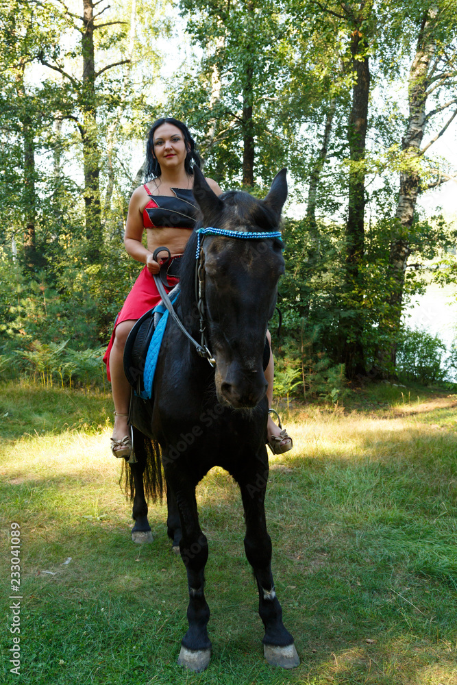 Beautiful brunette in a red suit of a dancer on horseback riding. Beautiful brunette in a red suit of a dancer on horseback riding.