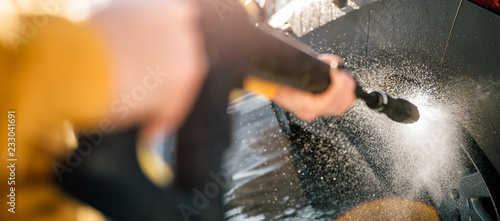Woman washing her car with pressure washer