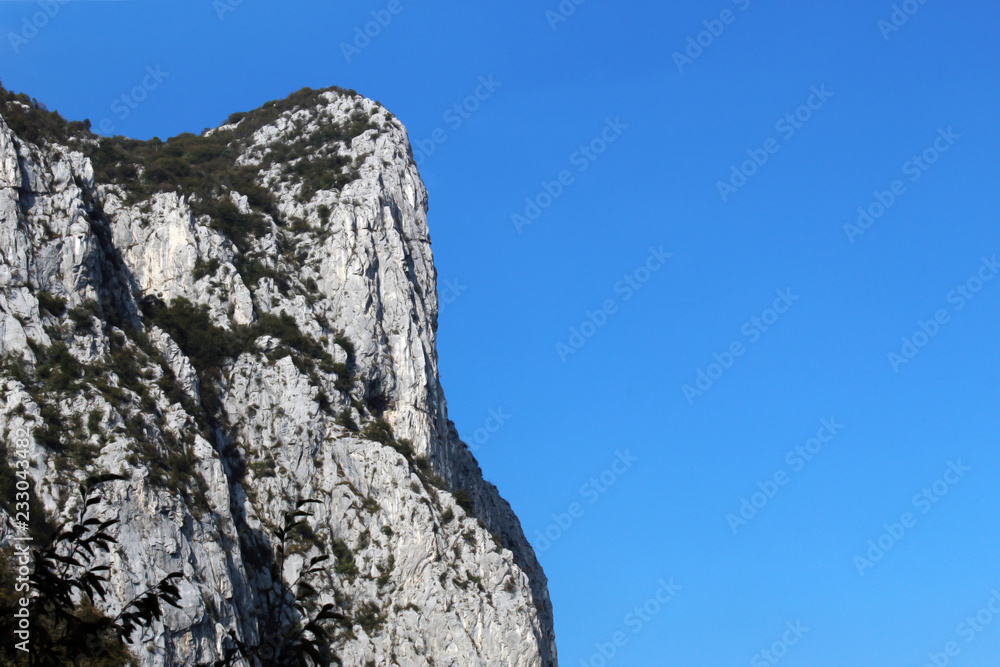 Vertical mountain cliff face against clear blue sky in summer Vertical mountain cliff face against clear blue sky in summer
