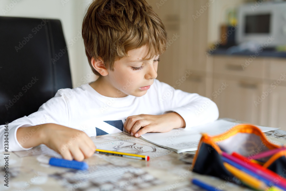Tired little kid boy at home making homework at the morning before the school starts. Little child doing excercise, indoors. Elementary school and education. Tired little kid boy at home making homework at the morning before the school starts. Little child doing excercise, indoors. Elementary school and education.