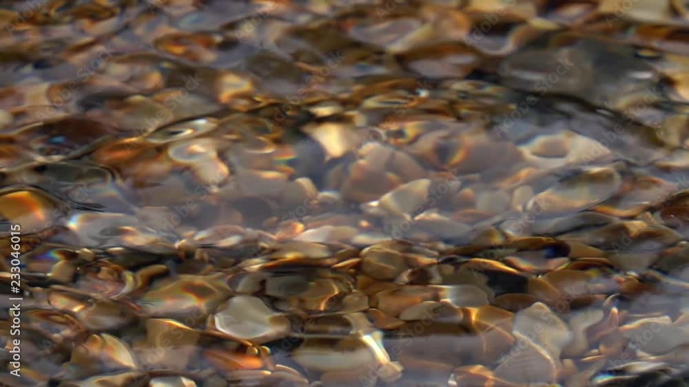 Slow motion of wave pattern with lattice structure in shallow pure water with brown pebble bottom close up. Side view of amazing natural background with vibrant texture in sun shine. High speed camera Slow motion of wave pattern with lattice structure in shallow pure water with brown pebble bottom close up. Side view of amazing natural background with vibrant texture in sun shine. High speed camera