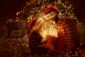 Family open Christmas Lighting Present Gift Box front of Xmas Tree, Happy Mother with Baby Child in Magic Night