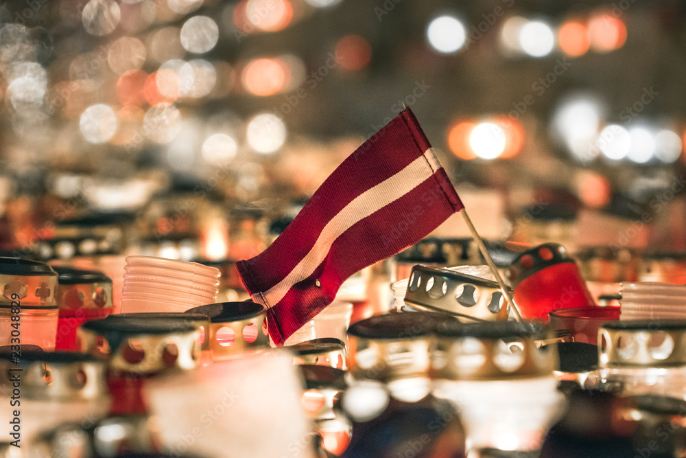 Latvian patriots lighting candles as a tribute to fallen freedom fighters. Hundreds of lighten up candles creating cosy atmosphere. Lāčplēša diena - day of independence of Latvia.  - obrazy, fototapety, plakaty 
