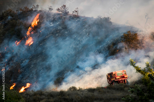 Bulldozer works on Burning Hillside During California Woolsey Brushire