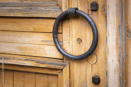 Obraz na plátně Brown wooden door with rusty old iron ring door handle