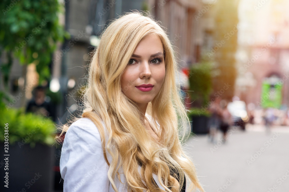 Beautiful young blond girl posing on street, closeup