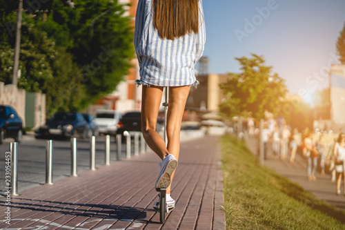 Beautiful girl riding a scooter down the street © teksomolika