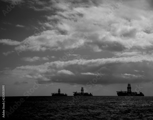 Backlit oil rigs and cloudy sky during the dawn, black and white